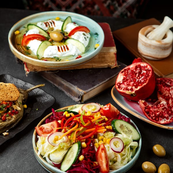 Three Mediterranean dishes: yogurt dip with cucumber and tomato, a colorful salad, and stuffed eggplant.