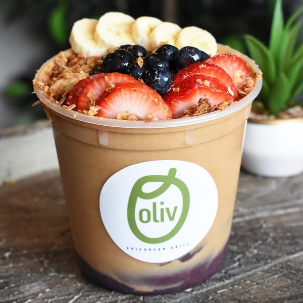Oliv Epicurean Grill smoothie bowl with bananas, blueberries, strawberries, and granola.